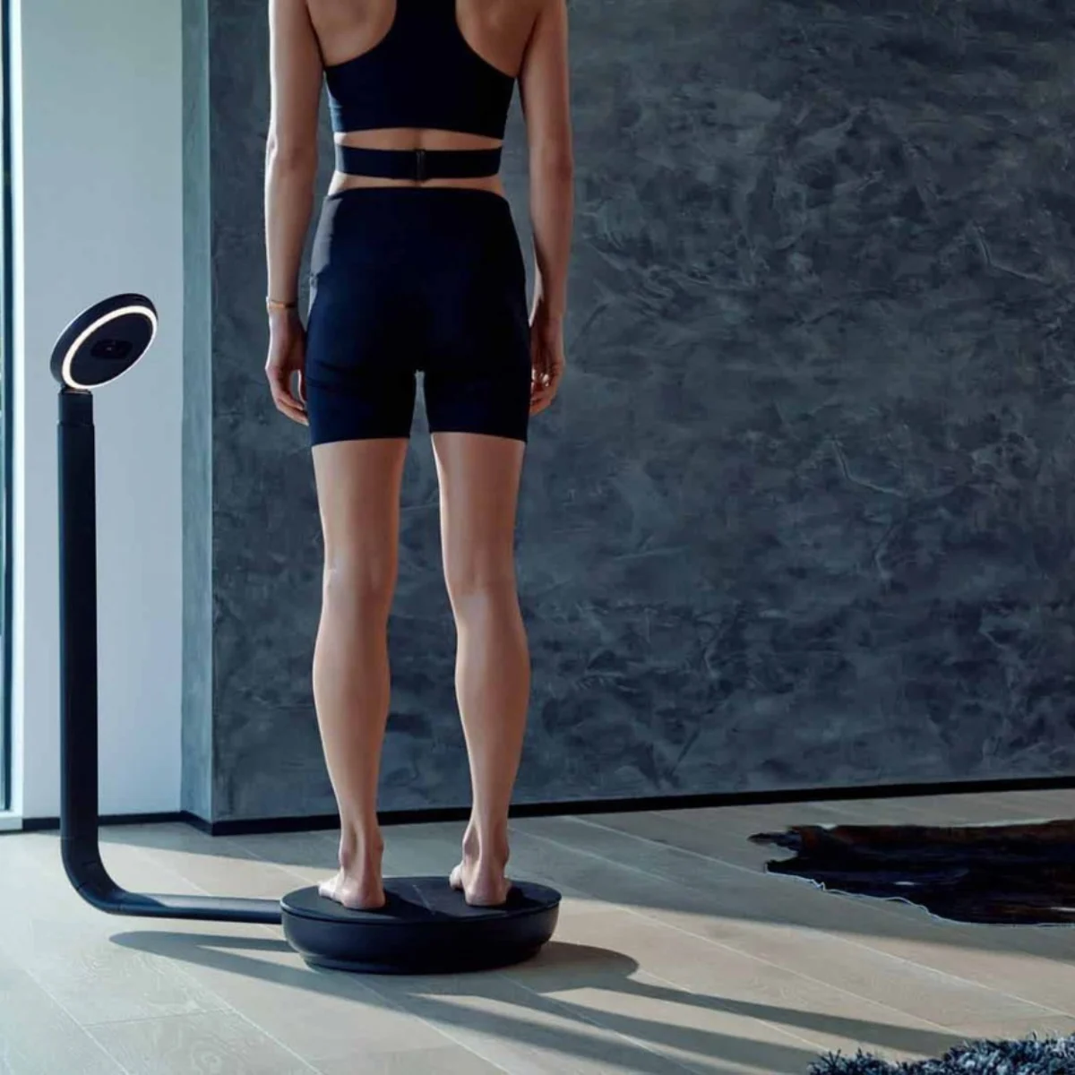 Woman standing on a ShapeScale 3-D body scanning platform beside the scanner